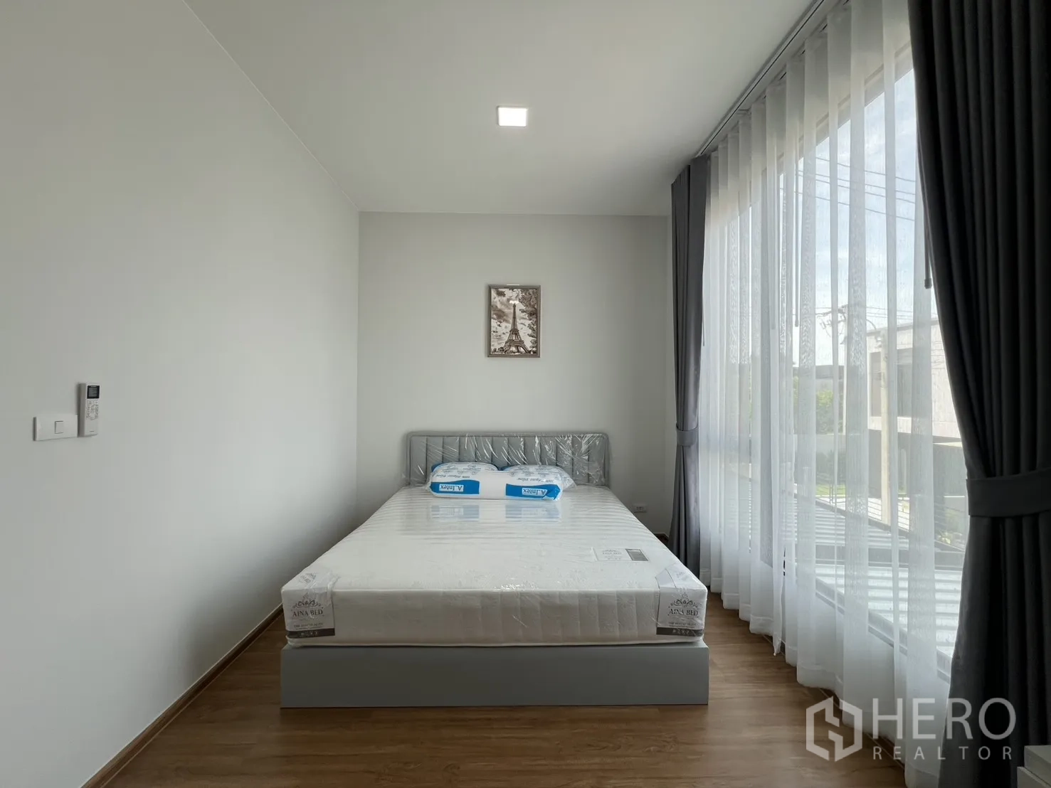 Townhouse for rent in Bang Phli, Samut Prakan - Master bedroom with queen bed facing a large sheer-curtained window.