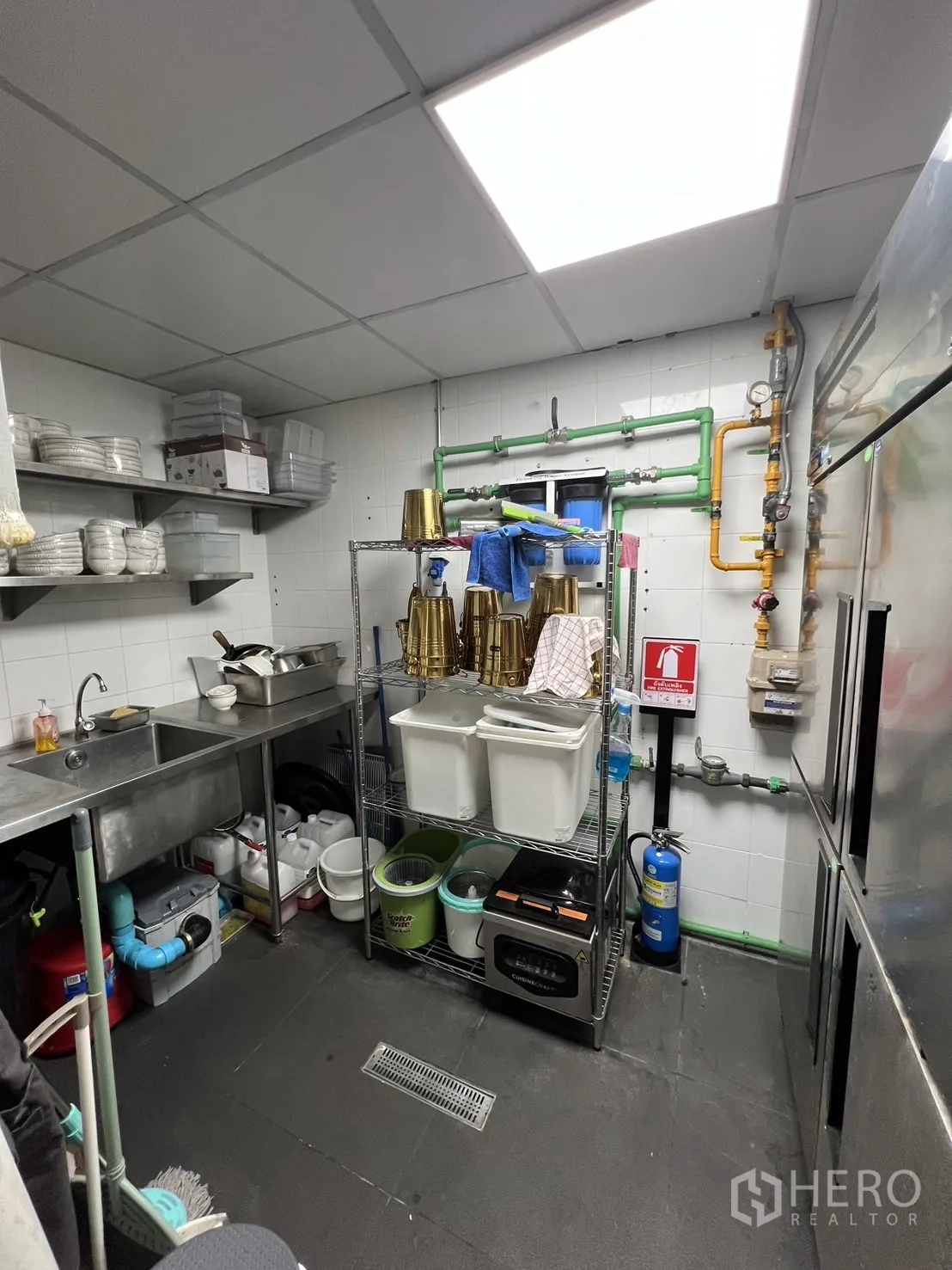 พื้นที่ขายปลีก ให้เช่า - ห้องล้างและเก็บของ อ่างล้างสแตนเลส ชั้นวาง และท่อระบายน้ำพื้น