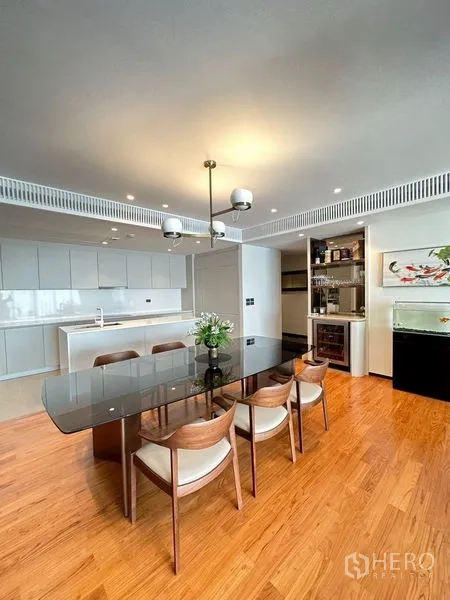 คอนโด ขายในWatthana, Bangkok - พื้นที่รับประทานอาหารแบบโอเพ่นแปลน โต๊ะกระจก โคมไฟแขวน และครัวสีขาวพร้อมไอส์แลนด์ พื้นไม้โทนอุ่น