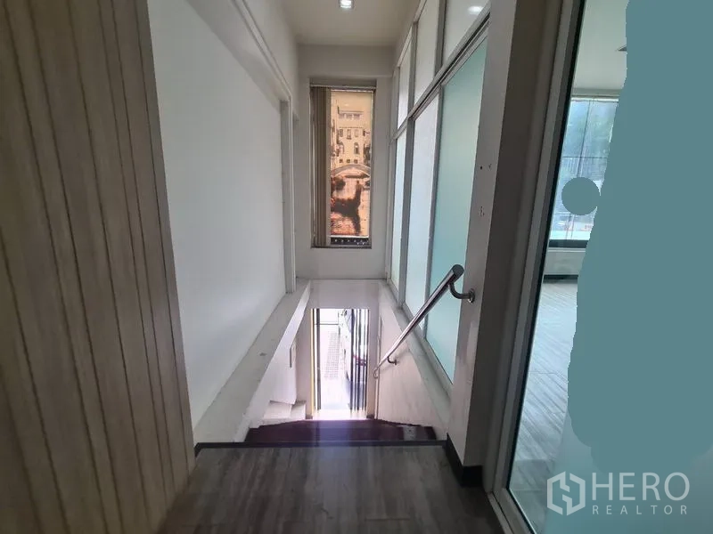 零售空间 出租在Watthana, Bangkok - 室内楼梯平台，玻璃墙与扶手通往街面。