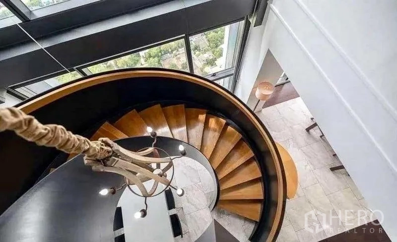 Condominium for rent - Curved spiral staircase linking duplex levels beside tall glass windows.