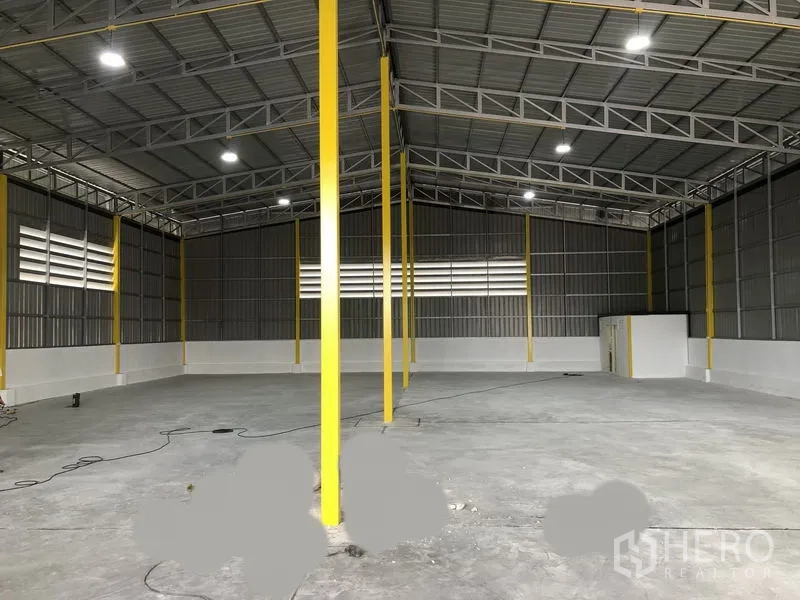 货栈 出租在Pathum Thani - 仓库内部宽敞，高钢结构与黄色立柱，LED照明，混凝土地面