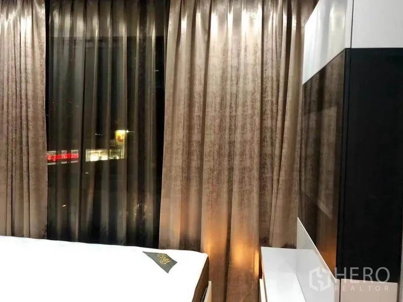 คอนโด ให้เช่าหรือขายในPhaya Thai, Bangkok - ห้องนอนพร้อมผ้าม่านสูงจรดเพดานและแสงไฟเมืองยามค่ำจากหน้าต่าง