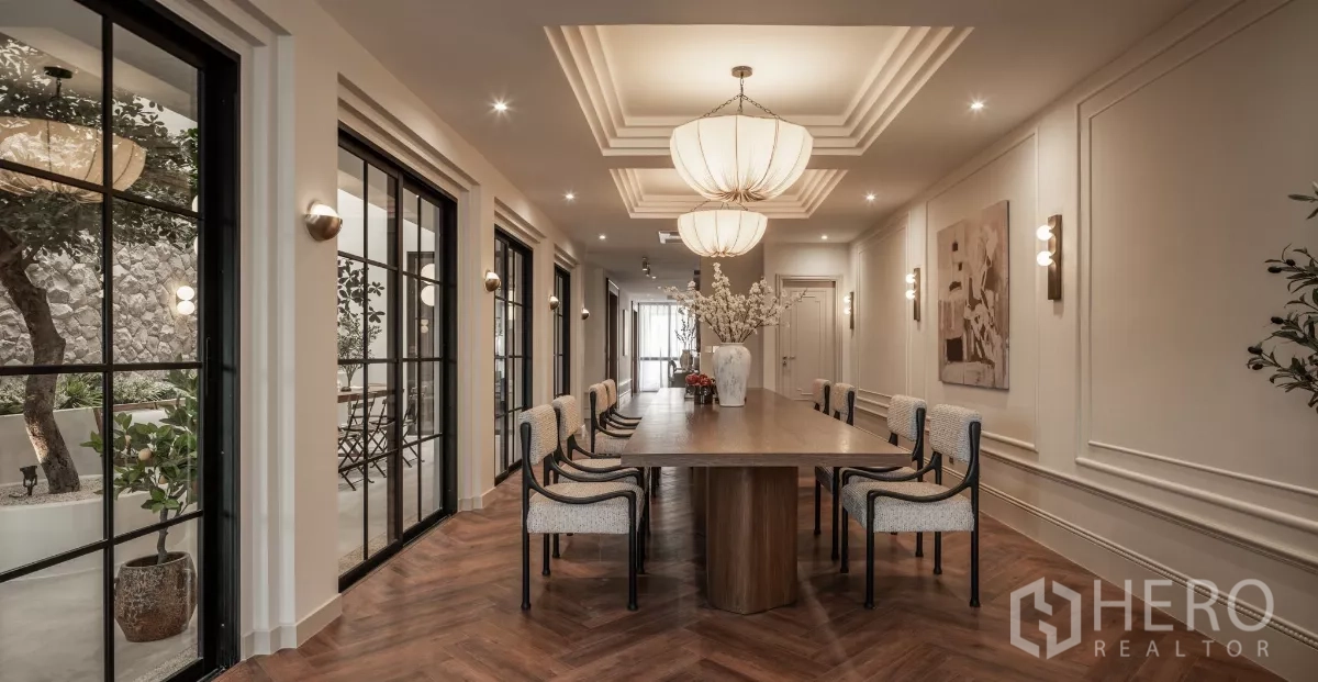 带办公室的家 出售在Phra Khanong, Bangkok - 雅致会议/餐厅，长桌、人字拼木地板与吊灯，面向庭院。