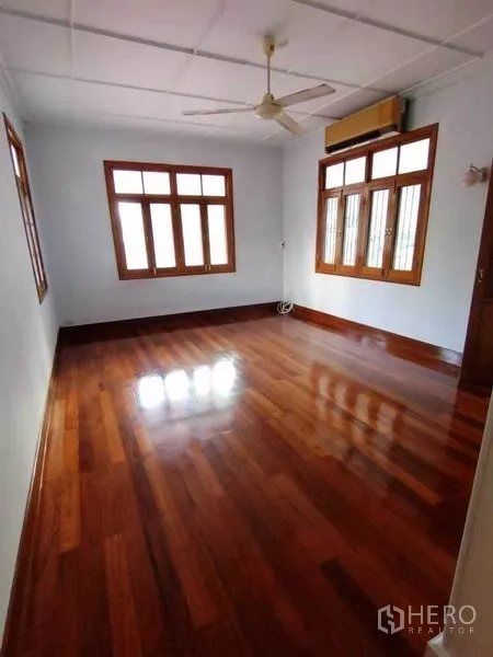 Detached House for rent in Pathum Wan, Bangkok - Bedroom with two walls of wood-framed windows, ceiling fan and air conditioner.