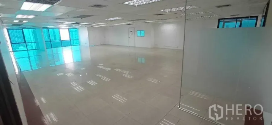 办公空间 出租在Huai Khwang, Bangkok - 宽阔办公楼层，玻璃隔断、瓷砖地面与蓝色镀膜窗引入自然光。