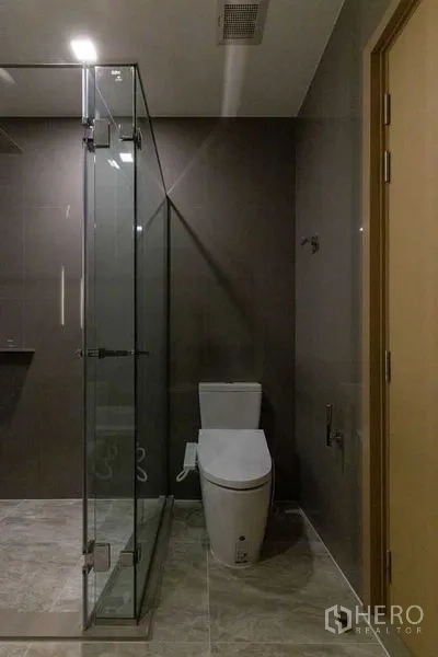 คอนโด ให้เช่าในWatthana, Bangkok - ห้องน้ำร่วมสมัย พร้อมตู้กระจกอาบน้ำและโถสุขภัณฑ์สีขาว ผนังโทนเข้ม