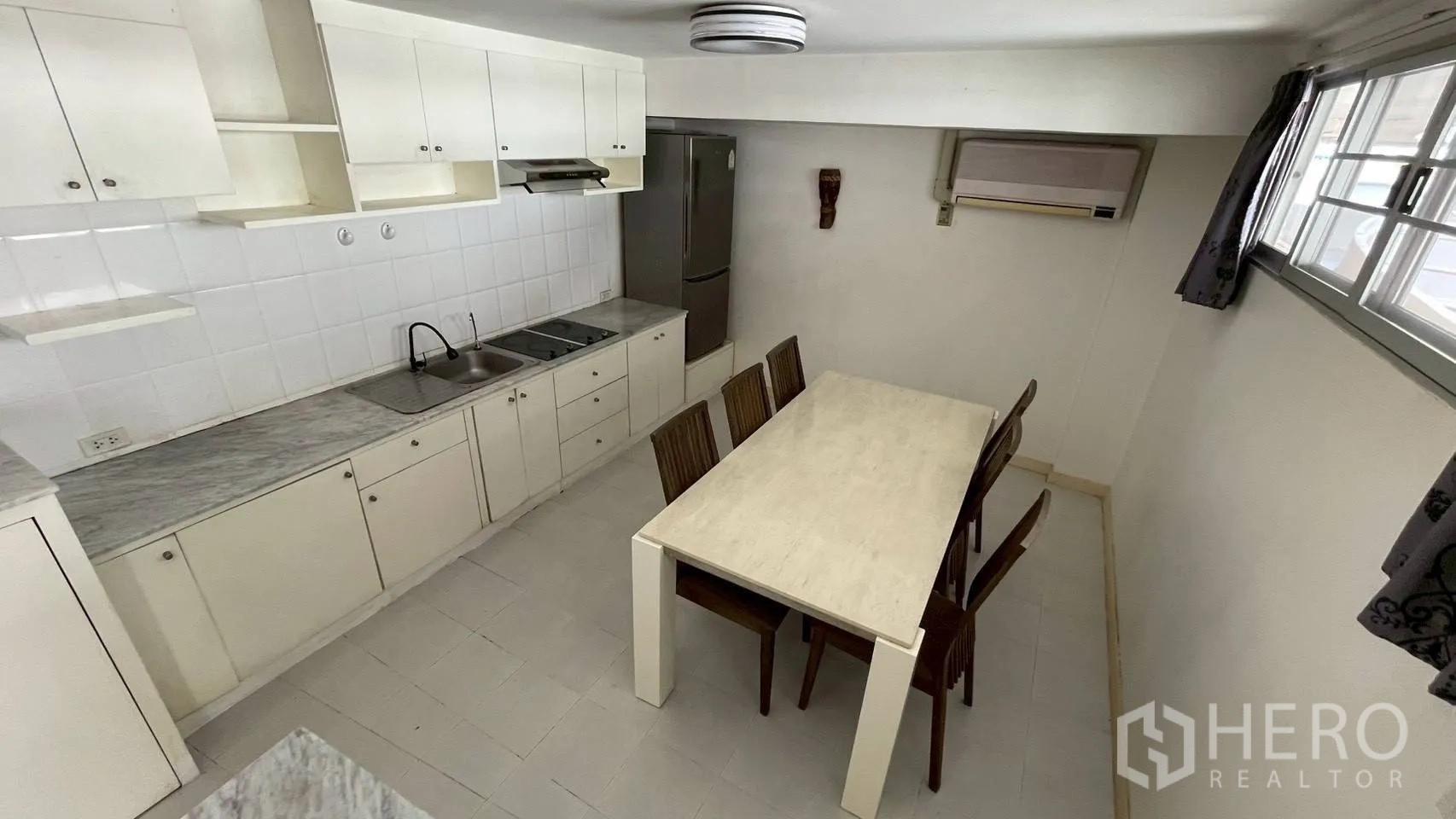 Condominium for sale in Wang Thonglang, Bangkok - Eat-in kitchen with marble-look counters, 4-ring electric cooktop and dining table.