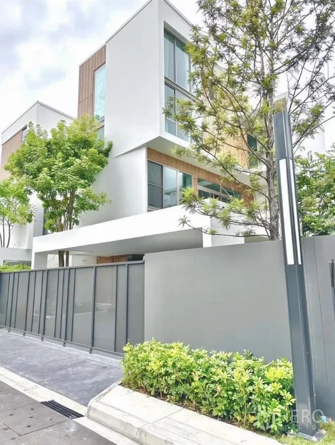 Detached House for rent in Saphan Sung, Bangkok - Corner view of minimalist white house with sliding perimeter gate and street frontage.