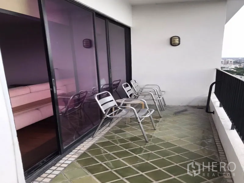Condominium for rent or sale in Watthana, Bangkok - Large balcony with outdoor chairs and sliding glass doors.