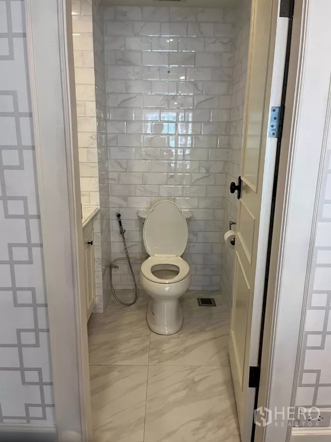 公寓 出租在Pathum Wan, Bangkok - 客卫间配坐便器、白色地铁砖与喷枪。