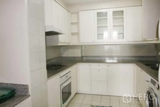 公寓 出租在Sathon, Bangkok - 封闭式U形厨房，白色橱柜，花岗岩台面，电炉、烤箱与洗衣机。