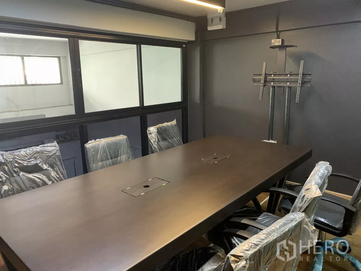 Home Office for rent in Pom Prap Sattru Phai, Bangkok - Enclosed meeting room featuring a long conference table, window panel and TV bracket.