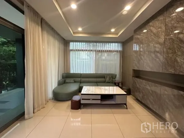 Detached House for rent in Bang Kapi, Bangkok - Corner lounge with floor-to-ceiling sheer curtains and a marble-top coffee table.