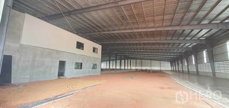 Factory for rent in Mueang Samut Sakhon, Samut Sakhon - Spacious factory interior with high steel truss roof, natural light, and partially finished concrete floor.