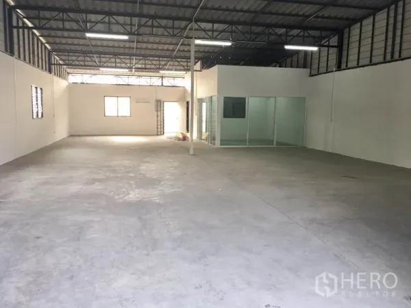 คลังสินค้า ให้เช่าในLam Luk Ka, Pathum Thani - พื้นที่จัดเก็บกว้าง เห็นโครงหลังคาเหล็ก หน้าต่างระบายอากาศ และห้องออฟฟิศกั้นกระจกภายในโกดัง.