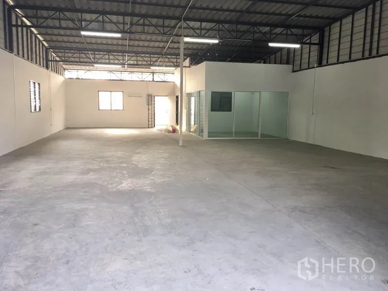 คลังสินค้า ให้เช่าในLam Luk Ka, Pathum Thani - พื้นที่จัดเก็บกว้าง เห็นโครงหลังคาเหล็ก หน้าต่างระบายอากาศ และห้องออฟฟิศกั้นกระจกภายในโกดัง.