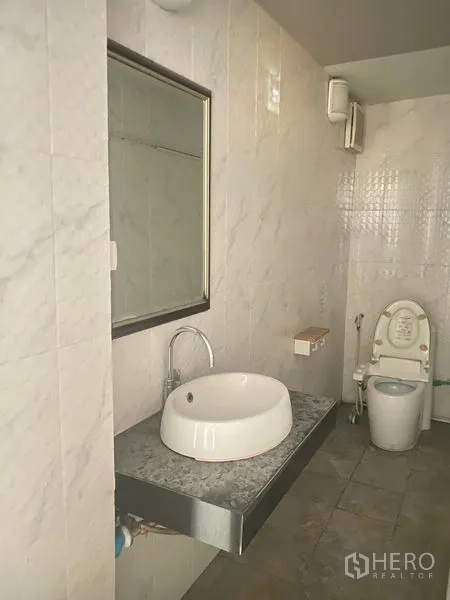 零售空间 出租在Watthana, Bangkok - 商铺内的瓷砖卫生间，带镜子、台上盆与坐便器。