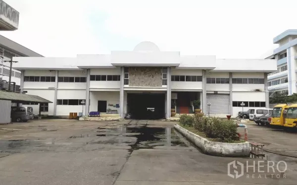 Factory for rent or sale in Bang Phli, Samut Prakan - Front elevation of a two-storey factory building with wide concrete driveway and loading bay.