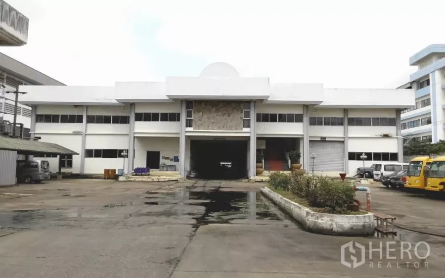 Factory for rent or sale in Bang Phli, Samut Prakan - Front elevation of a two-storey factory building with wide concrete driveway and loading bay.