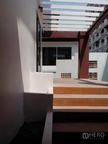 独立式住宅 出租在Phra Khanong, Bangkok - 前庭露台设格栅顶棚和台阶，连接推拉玻璃门。