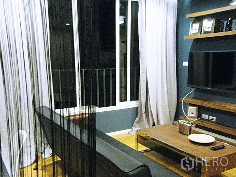 公寓 出租或出售在Bang Rak, Bangkok - 客厅设大窗与浅色窗帘，黑色线帘隔断和木质茶几。