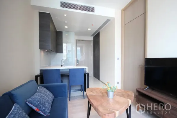 公寓 出租在Watthana, Bangkok - 温馨起居区，木质茶几面对电视，旁接吧台式厨房。