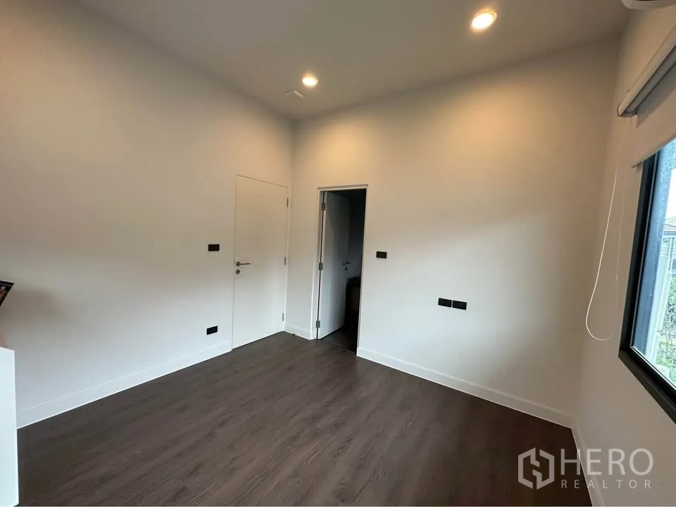 บ้านเดี่ยว for rent in Bang Kapi, Bangkok - ห้องโล่งพื้นลามิเนตสีเข้ม ไฟดาวน์ไลท์และหน้าต่าง