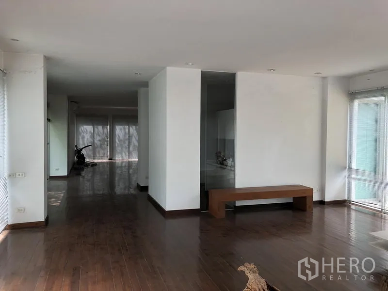 Factory for rent in Pathum Thani - Open-plan lounge with wide windows, white walls and polished wooden floors.