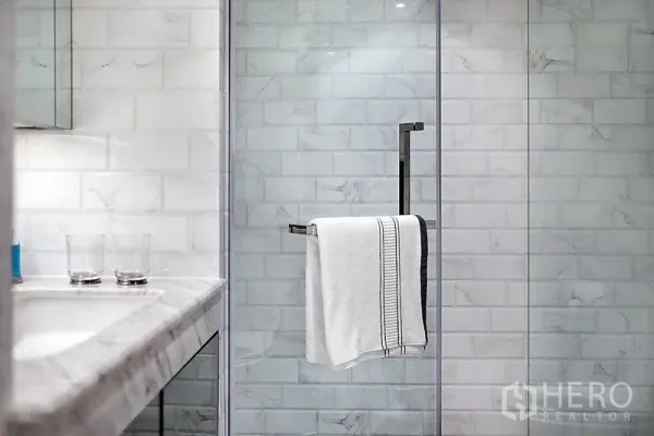 公寓 出租在Bang Rak, Bangkok - 现代浴室，石材台面与玻璃淋浴间，白色地铁砖墙面。