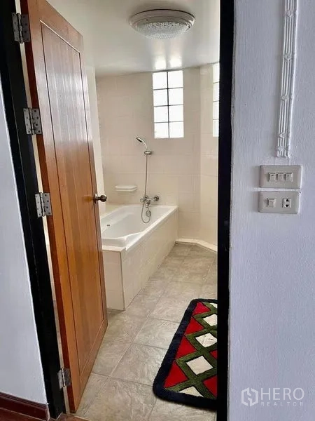 Home Office for rent - Tiled bathroom with a bathtub, handheld shower and glass block window.