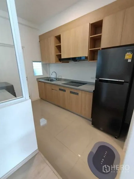 ทาวน์เฮาส์ ให้เช่าในPrawet, Bangkok - ครัวทางเดินตู้ไม้โทนอุ่น เตา ซิงก์ และตู้เย็นสีดำ