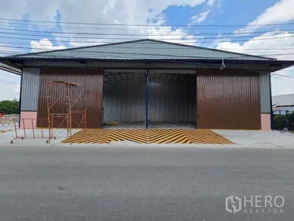 คลังสินค้า ให้เช่าในKhlong Toei, Bangkok - ด้านหน้าโกดังติดถนน ประตูสไลด์เหล็กบานกว้าง พร้อมทางลาดลายเหลืองดำ ในกรุงเทพฯ