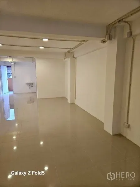 พื้นที่ขายปลีก ให้เช่า - ห้องโล่งยาว ผนังสีขาว เดินท่อโชว์ ไฟเพดาน และอ่างล้างมือ