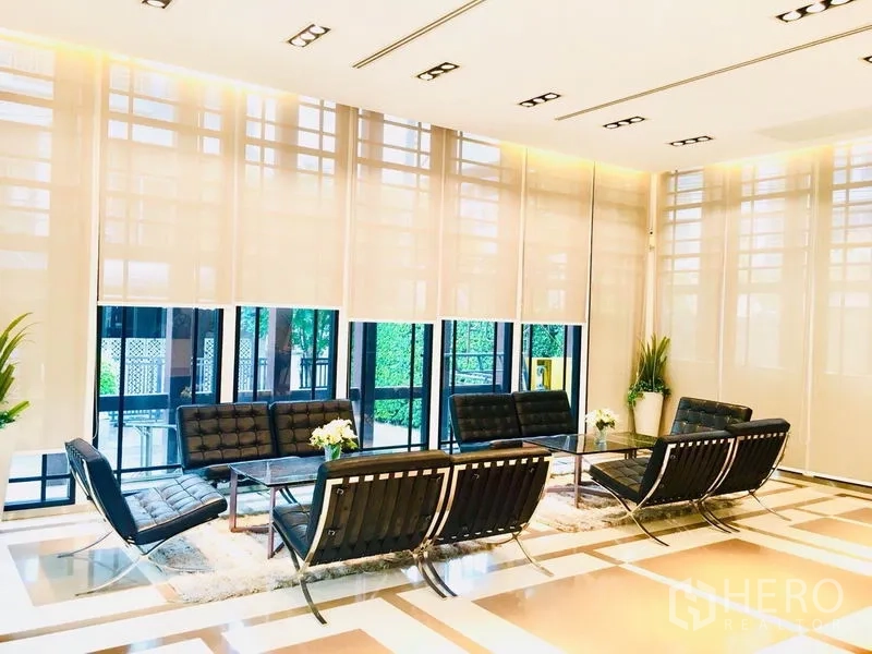 ทาวน์เฮาส์ ให้เช่าในPrawet, Bangkok - เลานจ์ส่วนกลางสว่าง ไฟธรรมชาติเต็มที่ เก้าอี้หนังสีดำ และต้นไม้ในอาคาร.