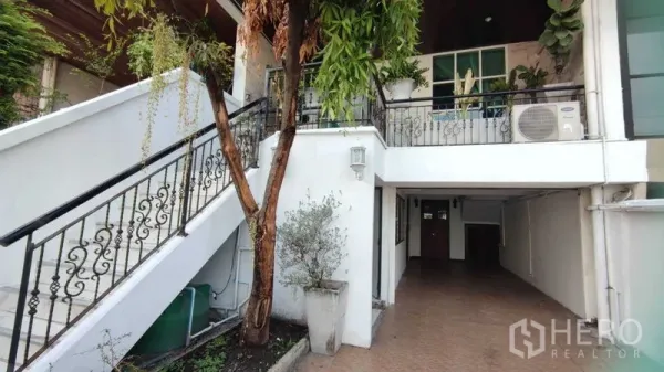 Home Office for rent in Watthana, Bangkok - Exterior of home office with wrought-iron stair, balcony planters and covered carport.