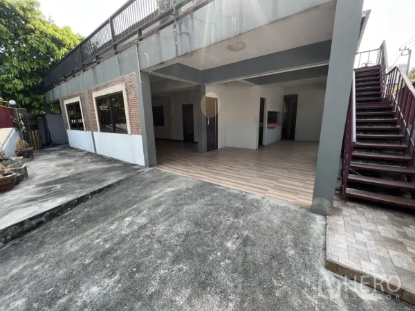 Home Office for rent in Watthana, Bangkok - Open carport and ground-floor space with striped tiles and side staircase access.