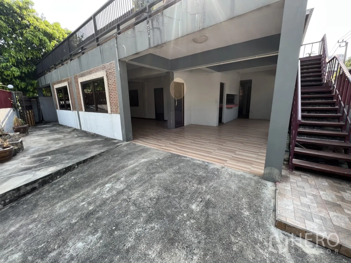 Home Office for rent in Watthana, Bangkok - Open carport and ground-floor space with striped tiles and side staircase access.