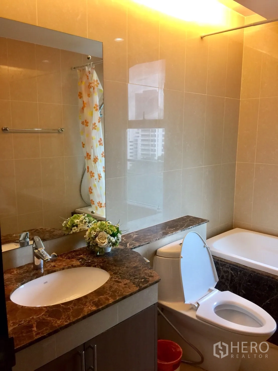Condominium for rent in Watthana, Bangkok - Second bathroom with marble countertop, large mirror, bathtub and window with partial city view.