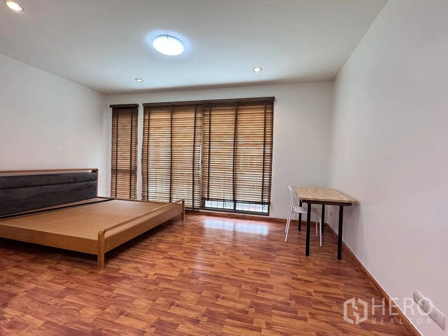 联排别墅 for rent in Phra Khanong, Bangkok - 宽敞卧室带木地板、书桌和大面积百叶窗。