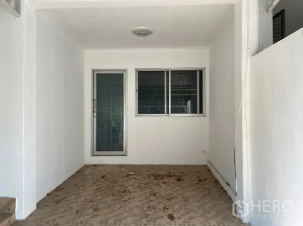 Townhouse for rent in Watthana, Bangkok - Covered entryway of the townhouse with security screen door, window and tiled floor.