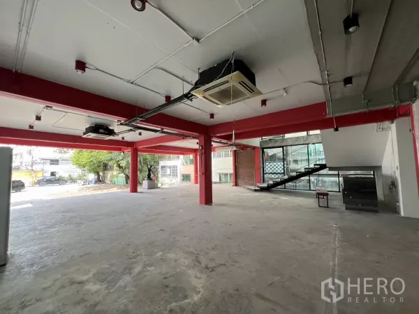 独立商业地产 出租在Din Daeng, Bangkok - 一层开放式空间，红色钢梁、清水混凝土地面与大窗。