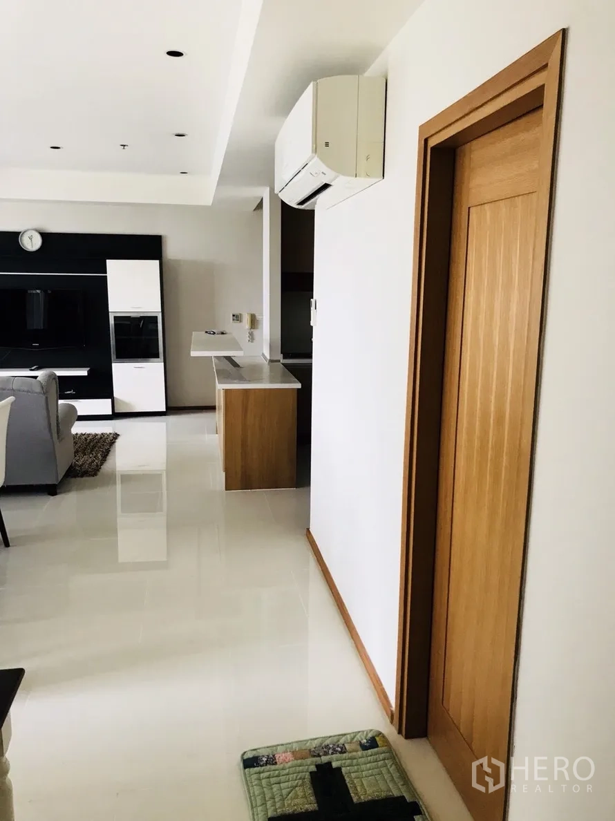 คอนโด ให้เช่าหรือขายในKhlong Toei, Bangkok - โถงนั่งเล่นแบบโอเพ่นพร้อมชั้นทีวี เคาน์เตอร์ครัว และประตูไม้พร้อมแอร์แขวนผนัง