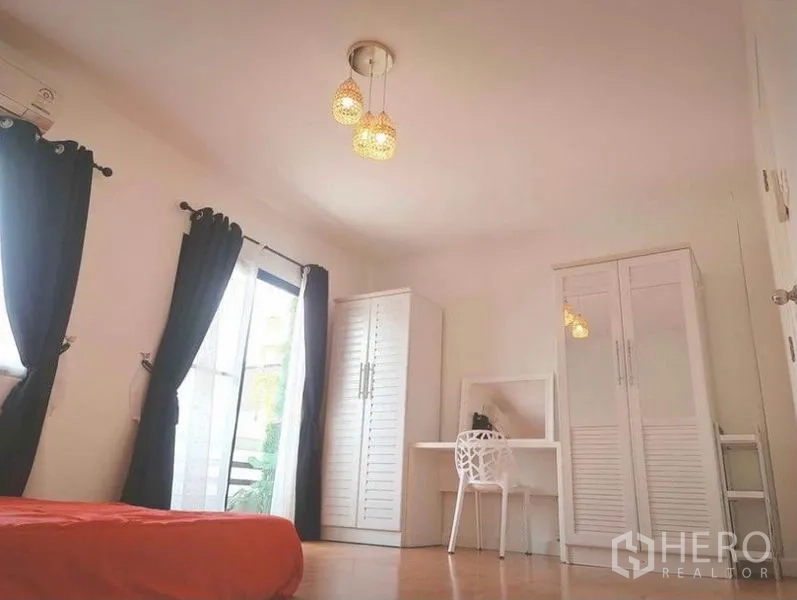 Townhouse for rent in Suan Luang, Bangkok - Bedroom with balcony access, white wardrobes, study desk and warm lighting