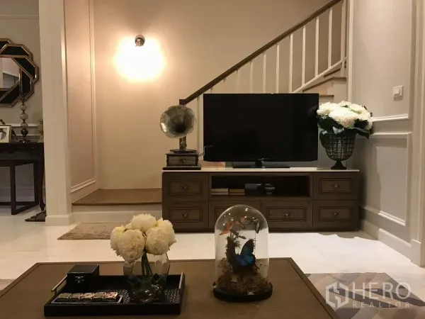 Townhouse for sale in Watthana, Bangkok - Cozy living area with TV console, staircase and decorative accents.