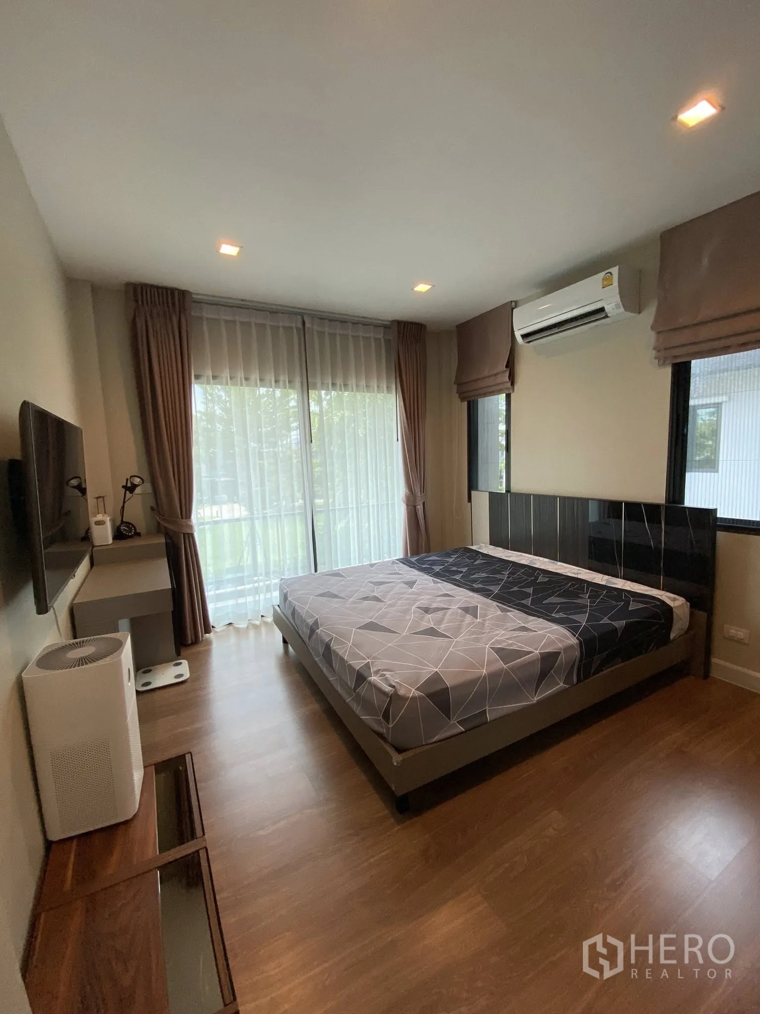 Detached House for sale in Saphan Sung, Bangkok - Primary bedroom with large windows, curtains, and wood flooring.
