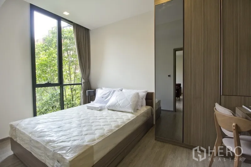 คอนโด ให้เช่าในWatthana, Bangkok - ห้องนอนมุมกระจกสูง เตียงคู่ ตู้เสื้อผ้าบิวท์อินและโต๊ะทำงาน พร้อมวิวต้นไม้
