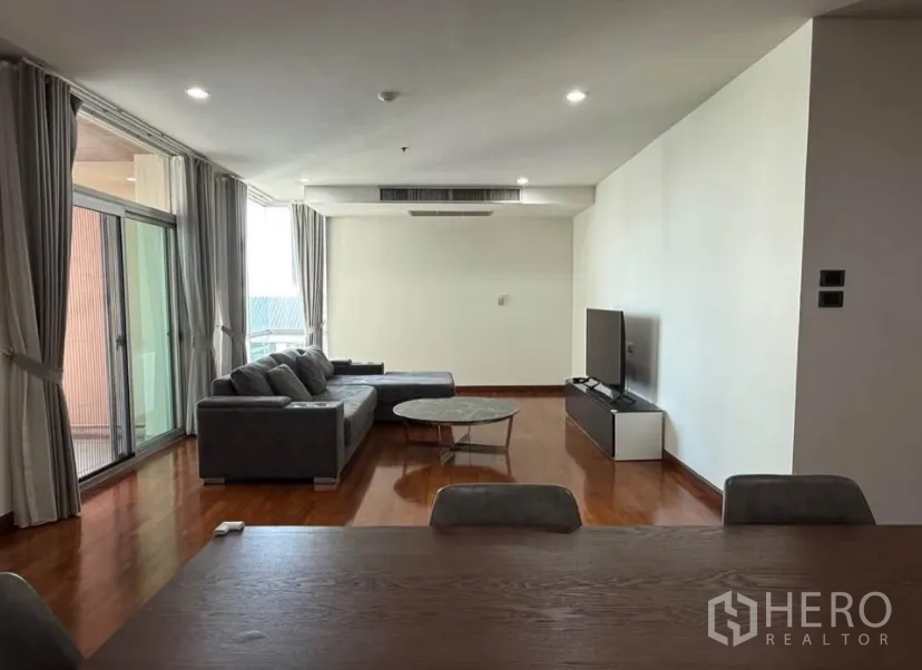 คอนโด for rent in Pathum Wan, Bangkok - พื้นที่นั่งเล่นเปิดสู่ระเบียงผ่านประตูกระจกบานเลื่อนพร้อมผ้าม่าน