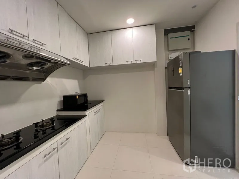 Detached House for rent in Bang Phli, Samut Prakan - Secondary kitchen with gas cooktop, upper cabinets and stainless fridge.