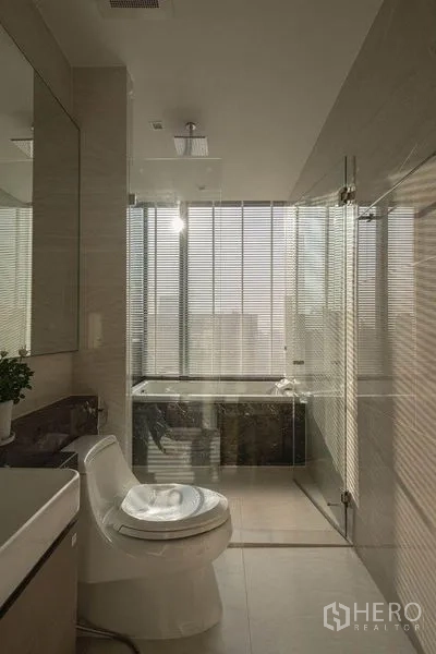 公寓 出租在Bang Rak, Bangkok - 现代卫浴，玻璃淋浴间、靠窗浴缸与城市景观。